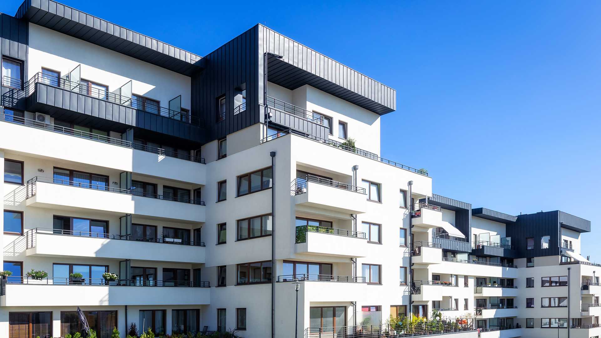 PMC Commercial Trust | SBA 7(a) Loans for Commercial Real Estate - White and black multifamily residential building with private balconies and large picture windows